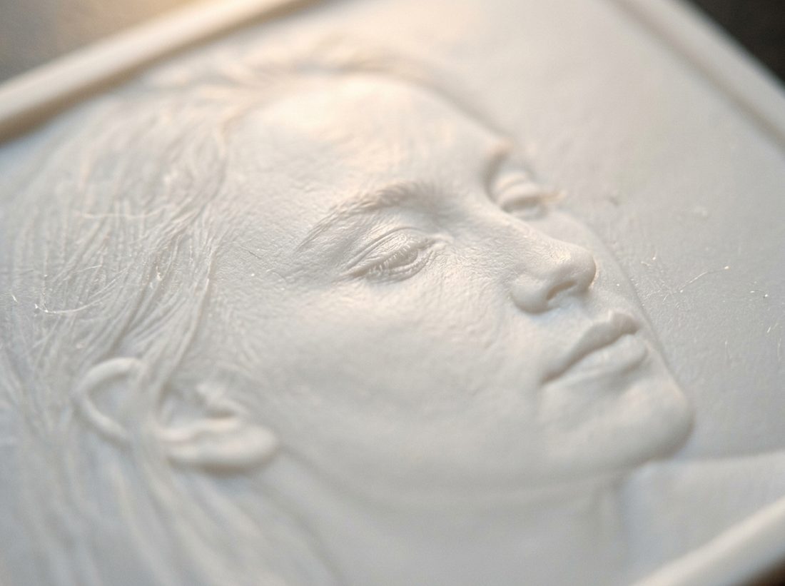 A carved white resin panel, its photo glowing through when lit